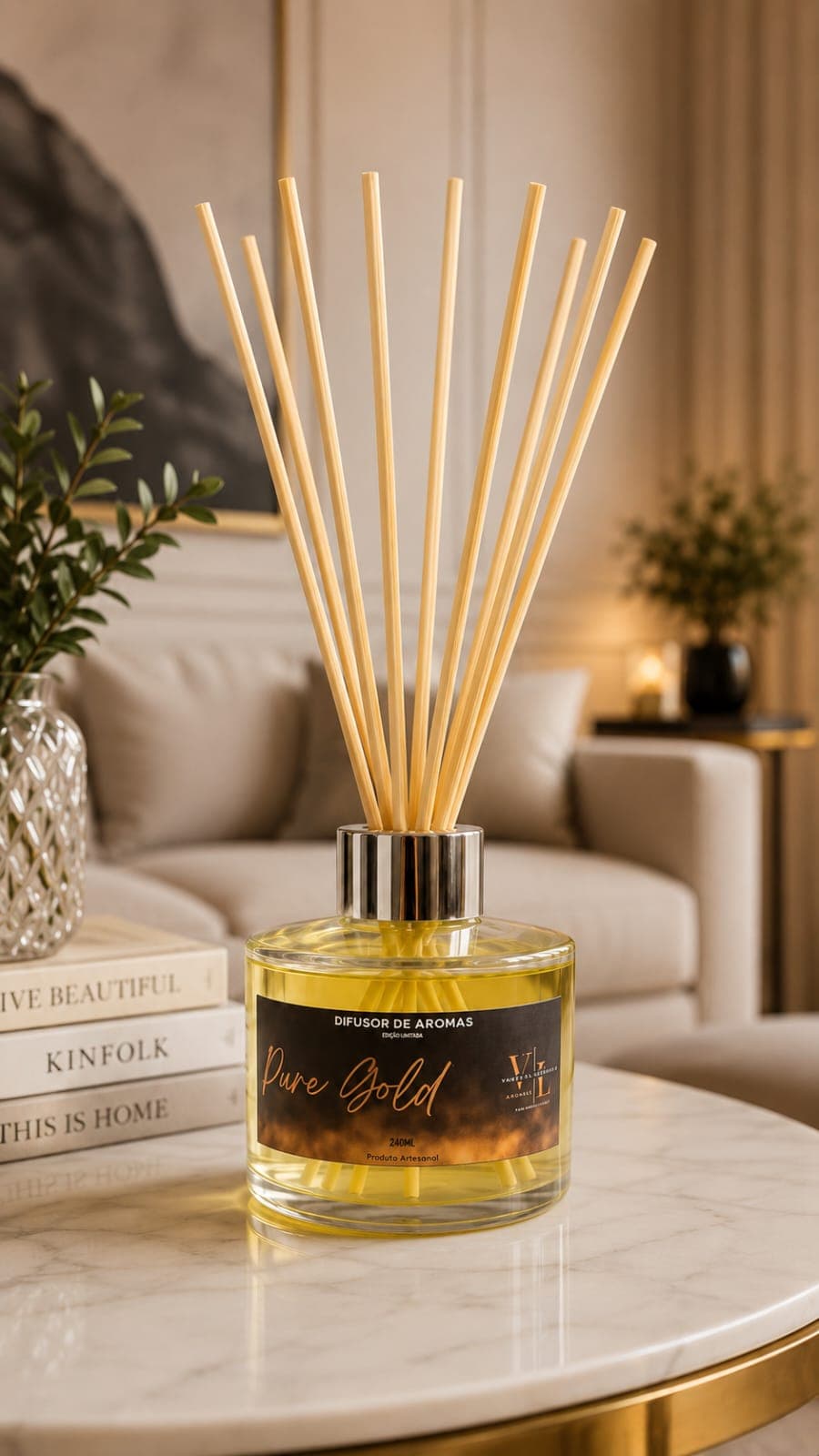 Difusor de aromas VL Aromas edição Pure Gold, frasco de vidro com líquido dourado e varetas de bambu, sobre mesa redonda de mármore com base dourada, em sala de estar sofisticada